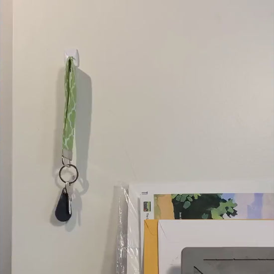 A keychain is shown being grabbed off of a hook on the wall, then placed in the pocket of a purse. Multiple different fabrics are then shown either being held in the hand or in the purse as a person walks to the door. 5 non spoonie fabric keychains are then shown on a white background.
