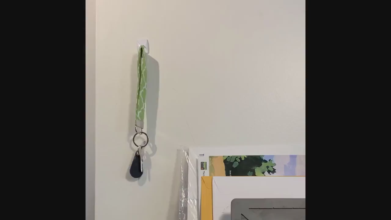 A keychain is shown being grabbed off of a hook on the wall, then placed in the pocket of a purse. Multiple different fabrics are then shown either being held in the hand or in the purse as a person walks to the door. 5 non spoonie fabric keychains are then shown on a white background.