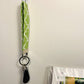A green keychain is shown hanging on a small command hook on the wall. There is a key and black fob attached to the key ring.
