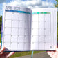 The monthly page is shown. This a calendar page with the month name and year at the top right and a notes writing area on the right side of the calendar box. There is a blue gradient from dark blue to aqua to green where the days of the week are- this is for the blue color journal. 
