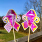 The word cloud and watercolor designs are shown on 2 sticks. Both ribbons feature a magenta/pink color and irregular yellow border on the edges. The design an awareness ribbon with a uterus in the center. The word cloud design on the left is split in half with a word cloud on the left half of the ribbon and right half of the uterus. 