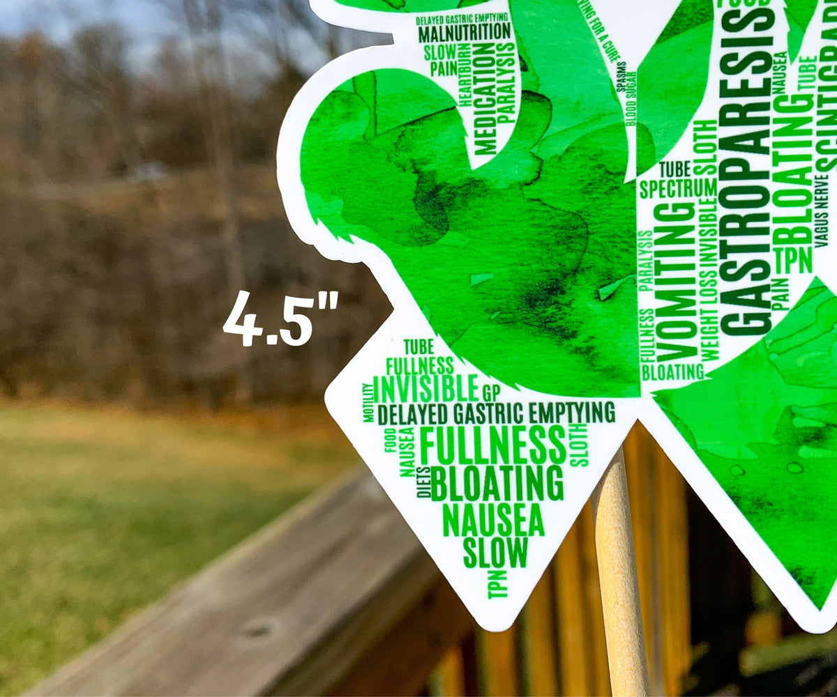 A close up of the 4.5 in word cloud ribbon is shown. You can see the words clearly in matching shades of green. The words are things like Gastroparesis, Invisible, Fullness, Slow, Paralysis, Pain, Tube, Malnutrition, Nausea, Spectrum, Spasms, and more.