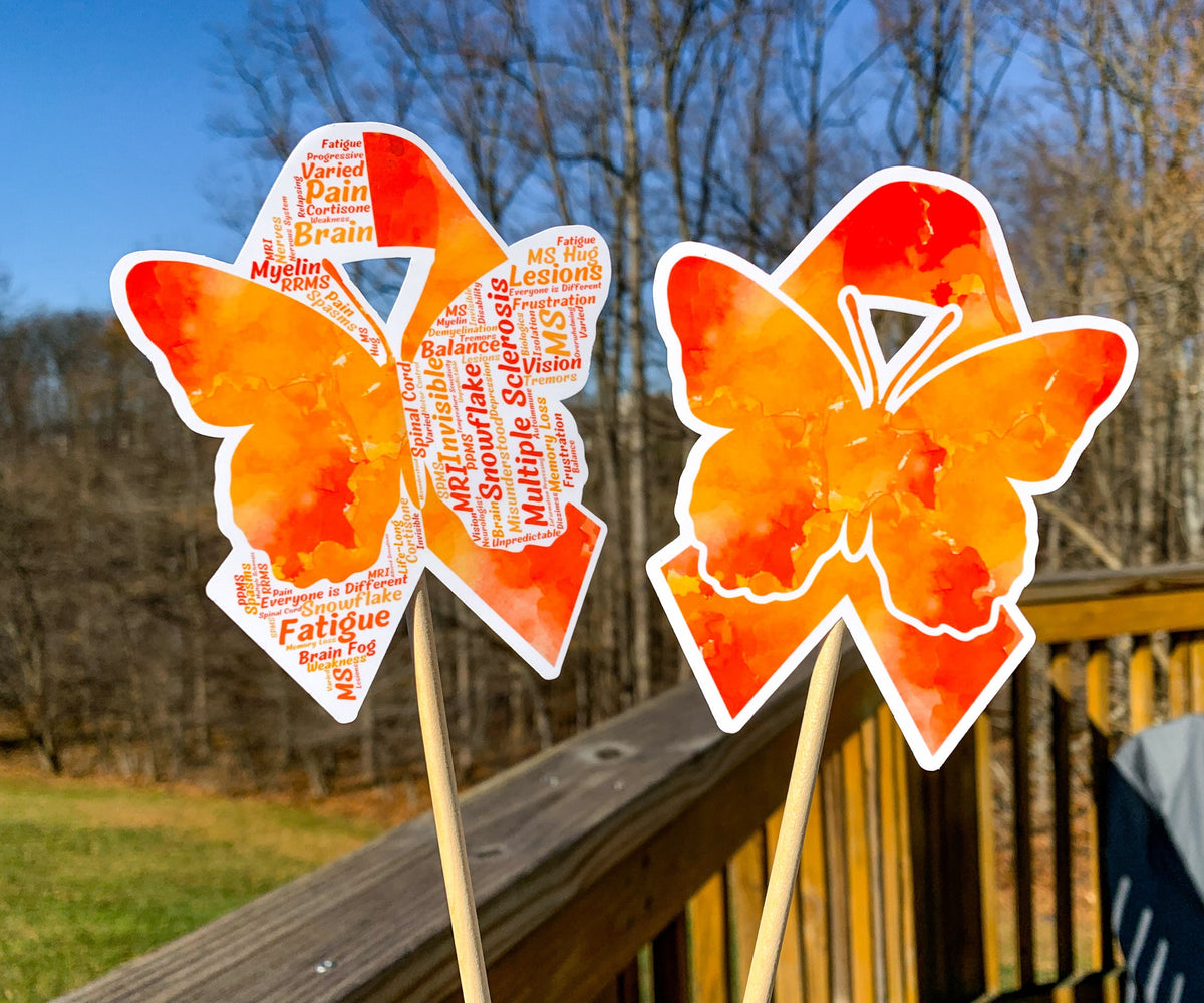 The word cloud and watercolor designs are shown on 2 sticks. Both ribbons feature an orange color awareness ribbon with a butterfly in the center. The word cloud design on the left is split in half with a word cloud on the left half of the ribbon and right half of the butterfly.