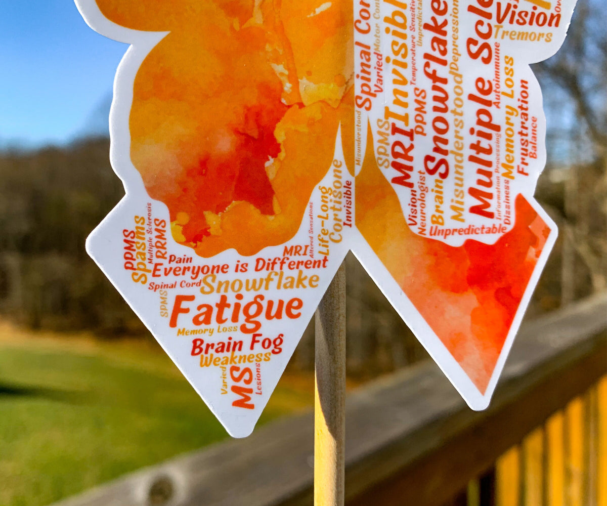 A close up of the 4.5 in word cloud ribbon is shown. You can see the words clearly in matching shades of orange. The words are things SPMS, Varied, Everyone is Different, Memory Loss, Frustration, Life-Long, Unpredicatable, Dizziness, MS, Misunderstood, Pain, and more.