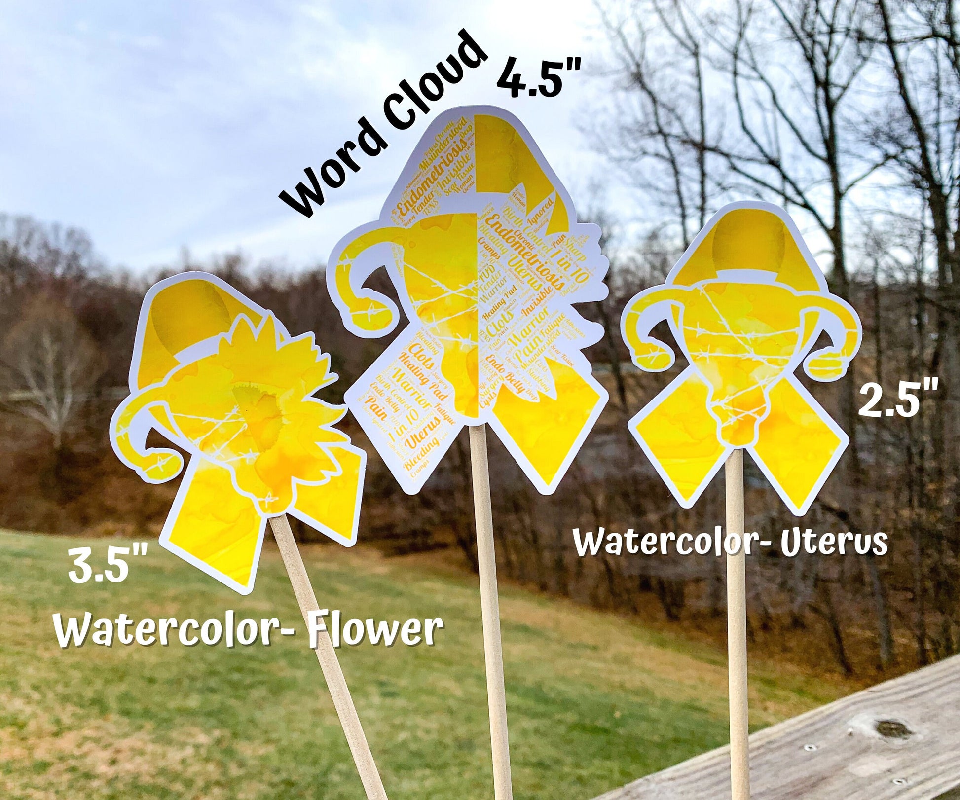  3 sizes of the stickers are shown. 3.5 inch, 4.5 inch, and 2.5 inch. It also shows that the watercolor design is all color and no word cloud and the word cloud is the design with each section split in half with the word clouds. There are two watercolor options. Watercolor Uterus has a uterus with barbed wire in the center of the ribbon and Watercolor Flower splits the uterus in half with a sunflower on the other side. 