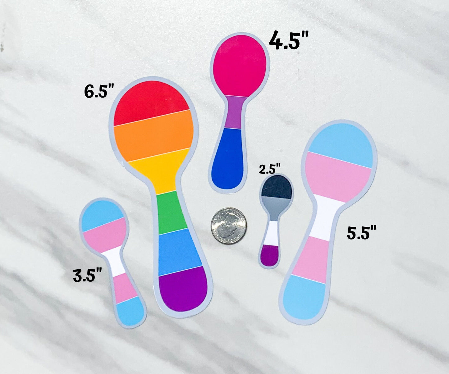6 sizes of pride spoon stickers are shown compared to the size of a US quarter. 2.5 inch asexual pride, 3.5 inch trans pride, 4.5 inch bisexual pride, 5.5 inch transgender pride, and 6.5 inch original rainbow pride.