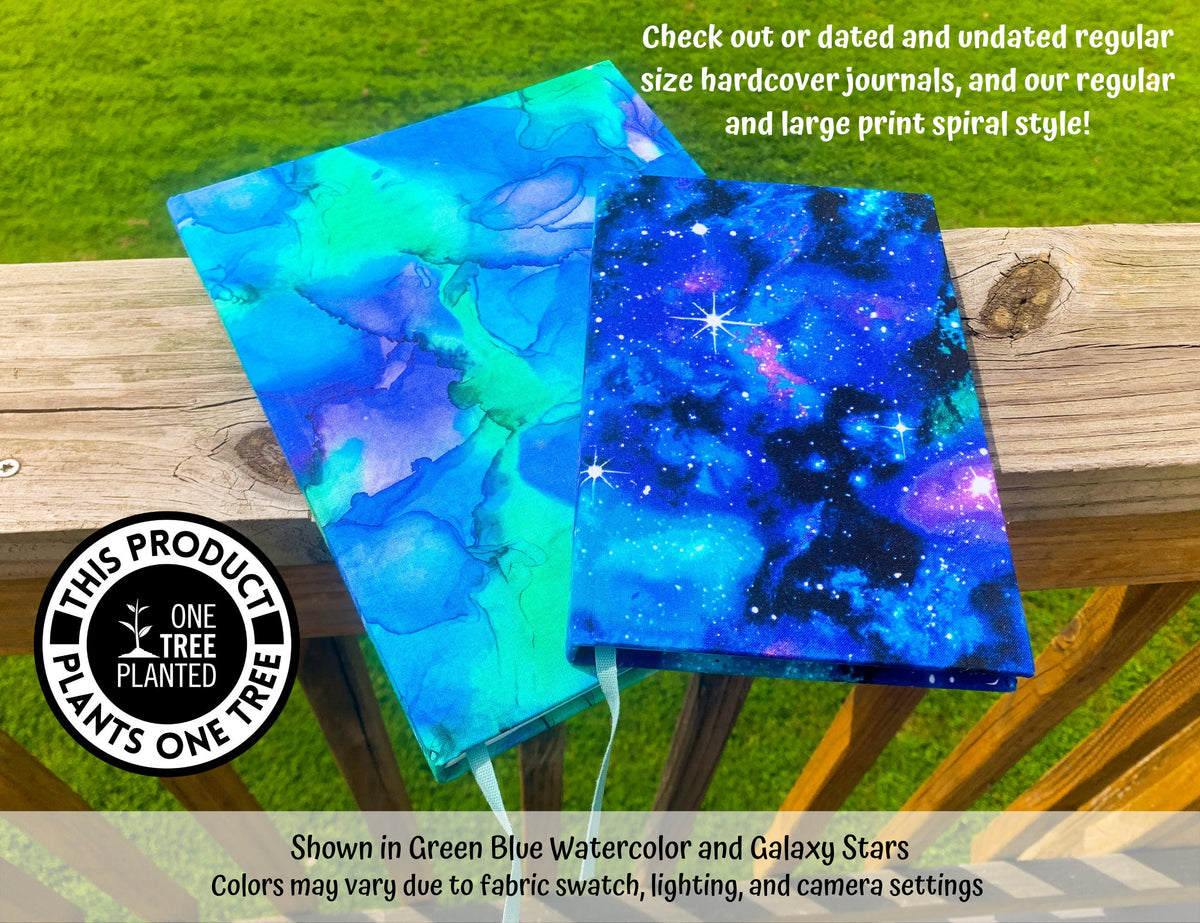 A regular sized journal is shown sitting on top of a large print book. A note says check out dated or undated regular size hardcover journals, and our regular and large print spiral style!. Shown in Green Blue Watercolor (Large Print) and Galaxy Stars (Regular). A logo in the bottom left says this product plants one tree.