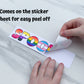 The spoonie sticker is shown being peeled off of the sticker paper backing. A note says the sticker comes on the sticker sheet for easy peel off. 